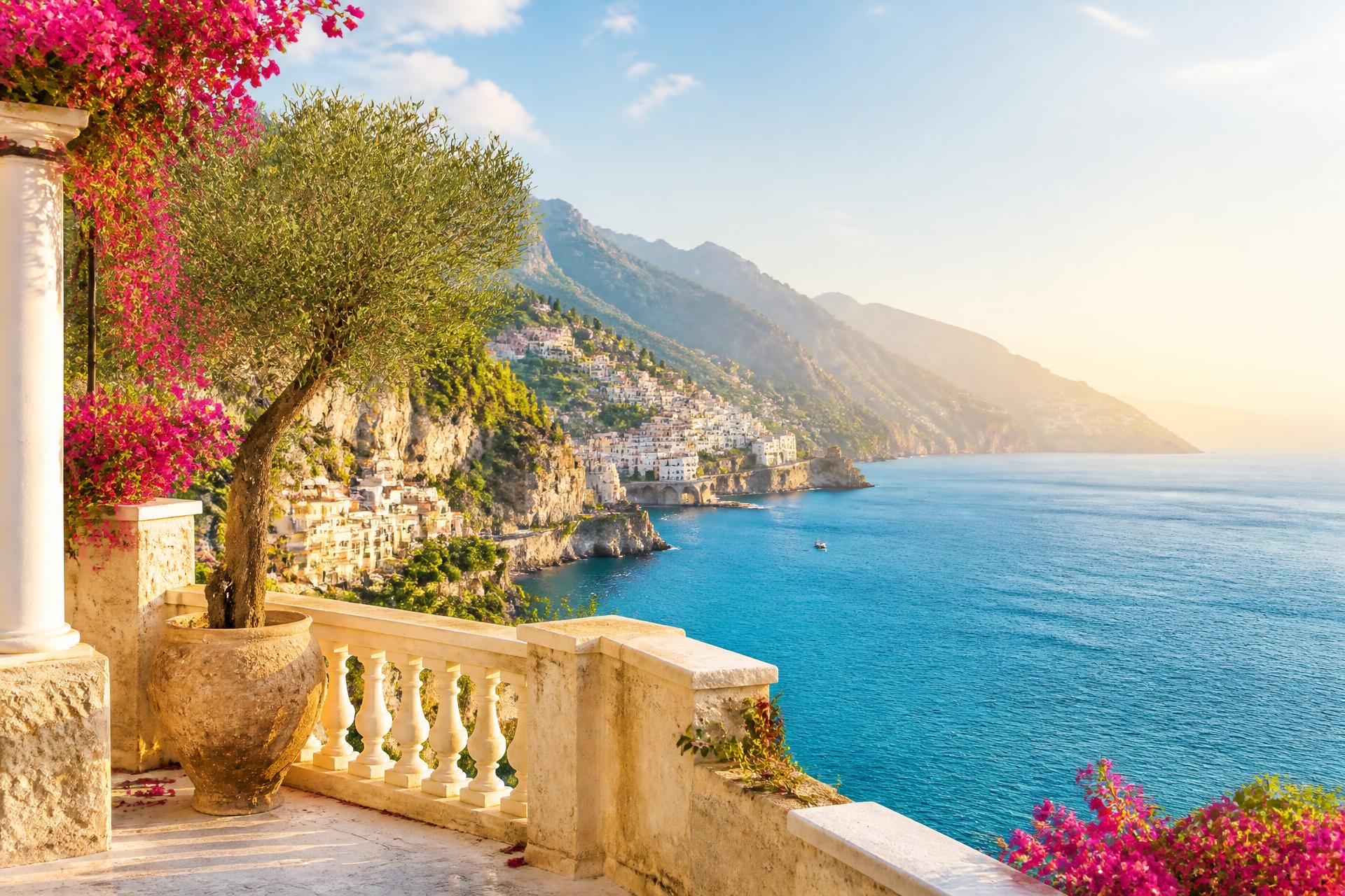 Sunlit Mediterranean terrace overlooking blue sea, coastal village and mountains